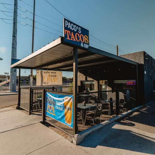 Paco's Tacos & Sip restaurant exterior with outdoor patio seating under a shaded awning.