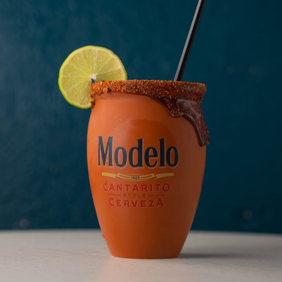 Modelo Cantarito Style Cerveza in an orange mug with a lime and chili-lime rim.