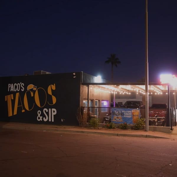 Paco's Tacos & Sip restaurant at night, with string lights illuminating the outdoor patio.